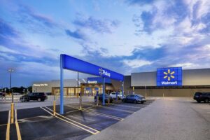 This July 2020 photo provided by Walmart shows the bright signage and Walmart logos from the parking lot outside the Walmart Supercenter in Springdale, Ark. Walmart is getting inspiration from the airport terminal as it revamps the layout and signage of its stores to speed up shopping and better cater to smartphone-armed customers.