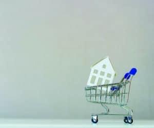 close up front view on house's model inside the shopping cart with copy space background for loan banking , home for sale and insurance concept
